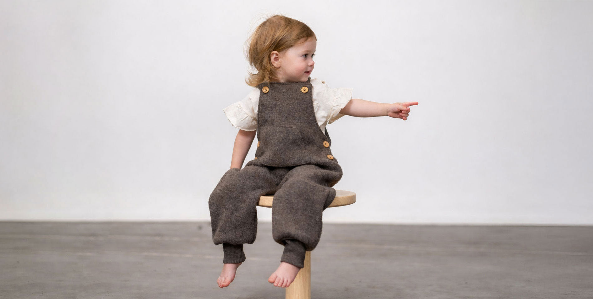 Kind mit Walk Latzhose auf Hocker