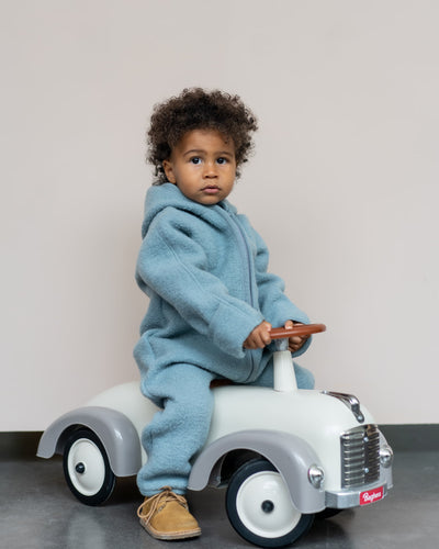 Baby mit Wollwalk Overall und Spielzeugauto